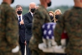 US President Joe Biden, first lady Jill Biden  look on as as a carry team moves a transfer a coffin wrapped in the US flag.