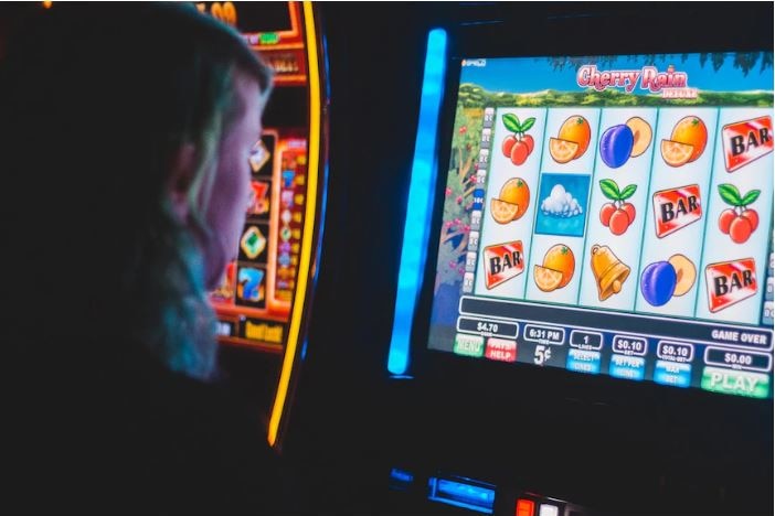 A person plays a poker machine in a dark room.