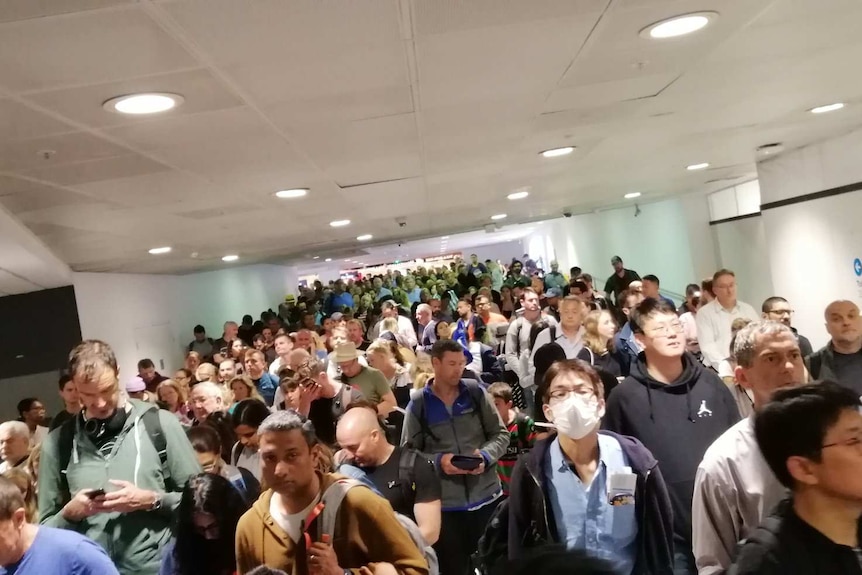 Crowds of people fill an airport corridor