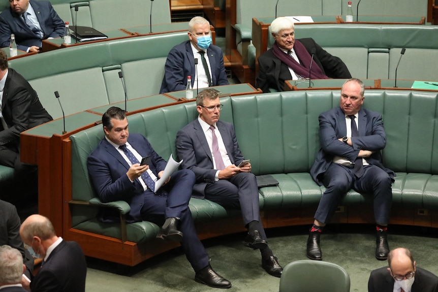 Sukkar and Tudge sit looking at their phones, and Joyce sits with his folded arms, on the opposition benches.