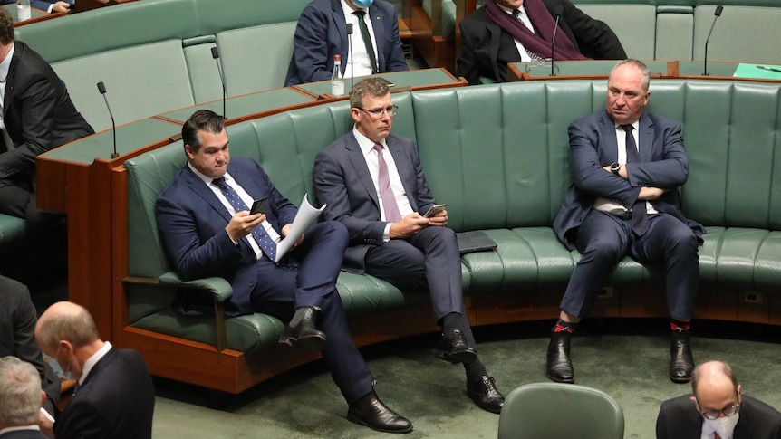 Sukkar and Tudge sit looking at their phones, and Joyce sits with his arms folded, on the opposition benches.