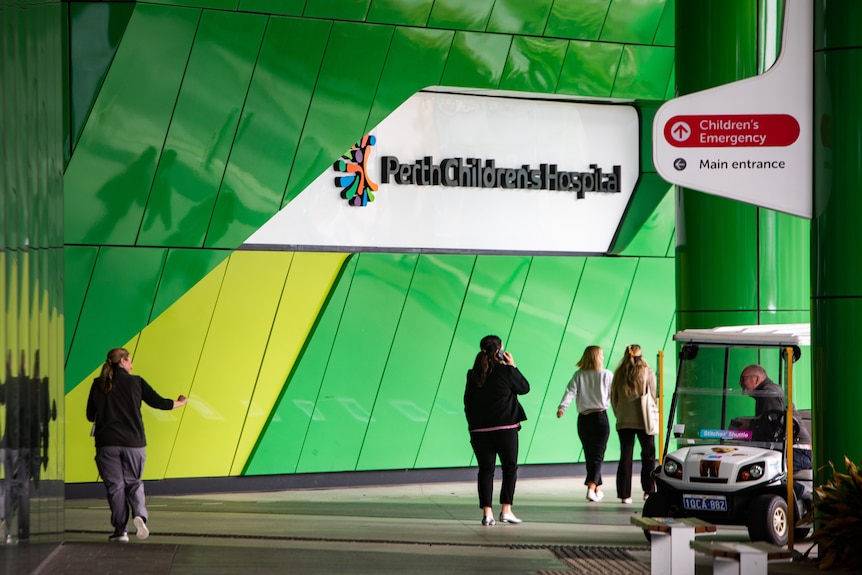 People walking underneath a sign for the Perth Children's Hospital.