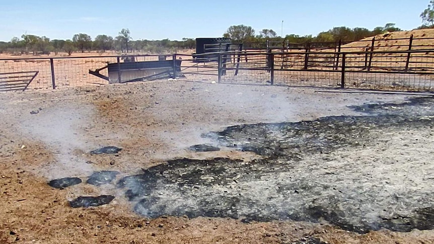 A fire burning in the ground in a cattle yards.