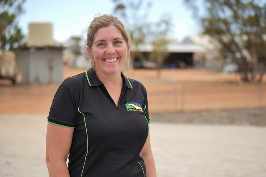 Female farmer standing by a homestead.