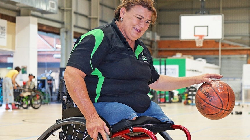Wendy playing wheelchair basketball on an indoor court.