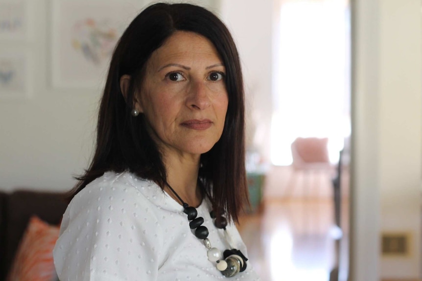 Corinne Brown standing in lounge room of her home, looking at camera