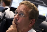 A trader looks worried as he sits at his desk in front of the DAX board at the Frankfurt stock exchange