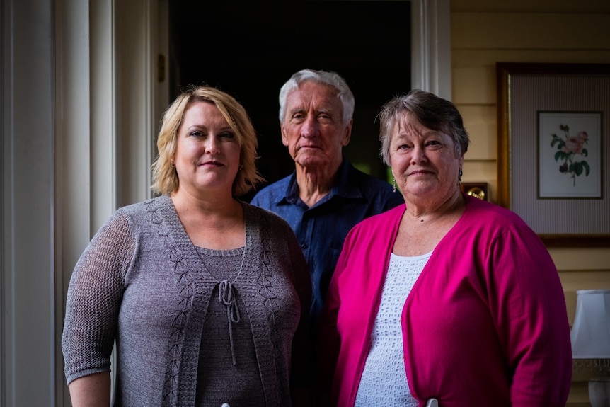 Karen Stewart, Brian Stewart and Val Stewart stand looking at the camera, neutral expressions on their faces.