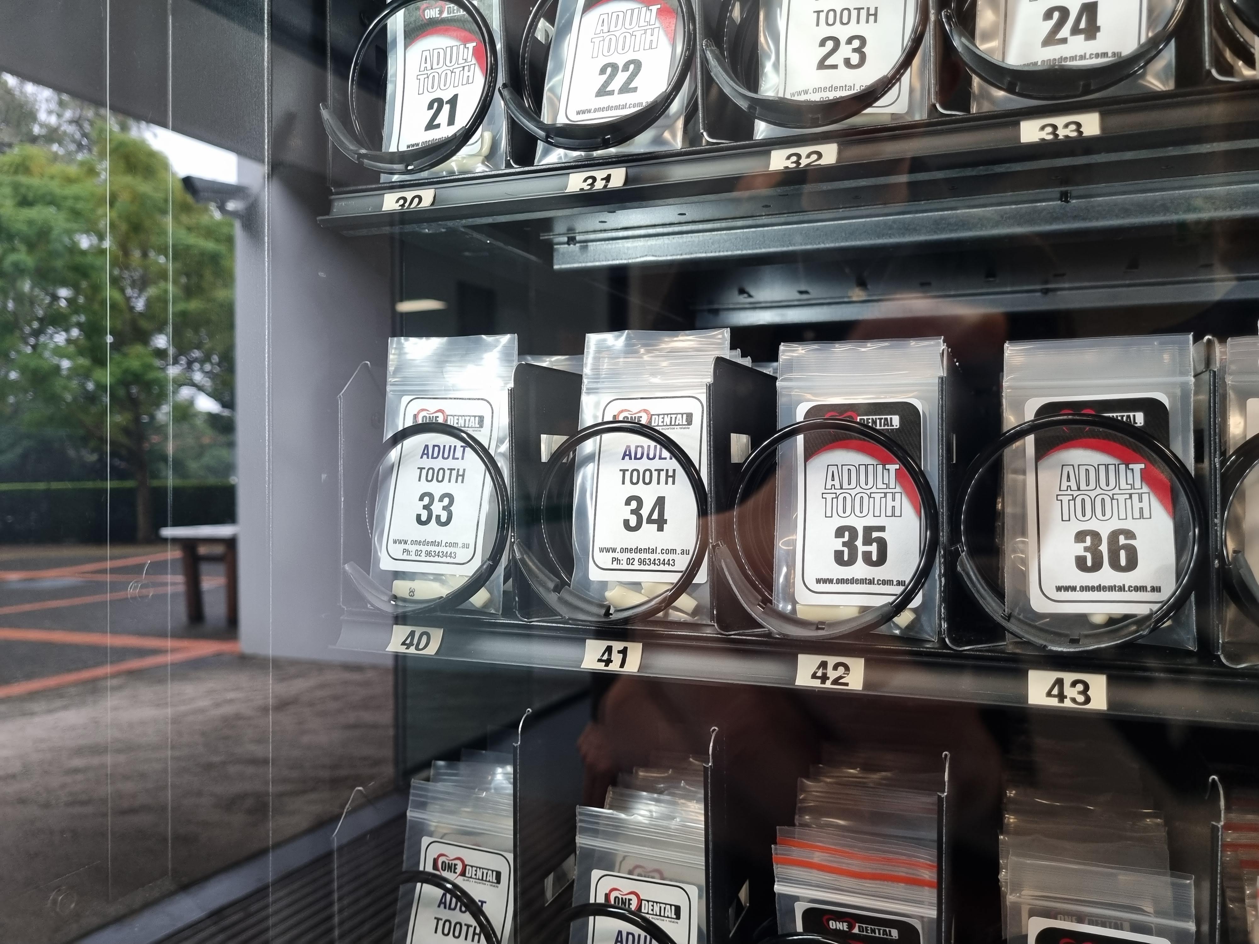 A close up of a vending machine containing rows of plastic teeth in small plastic bags.