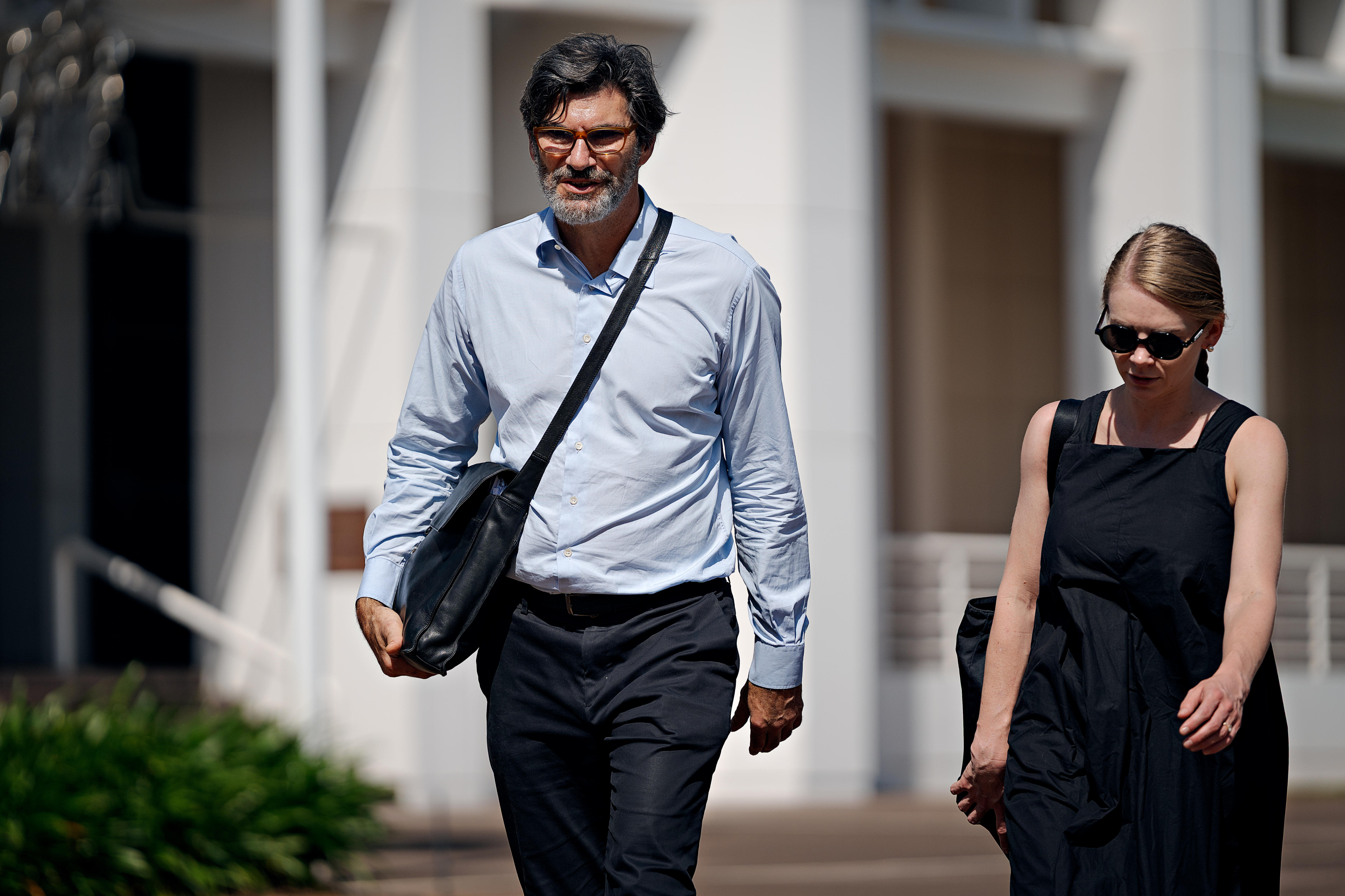 A man and woman in business clothes walking away from a courthouse. 