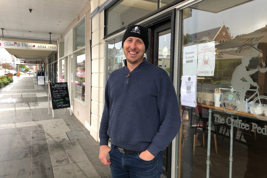 Man in navy jumper and black beanie, smiling