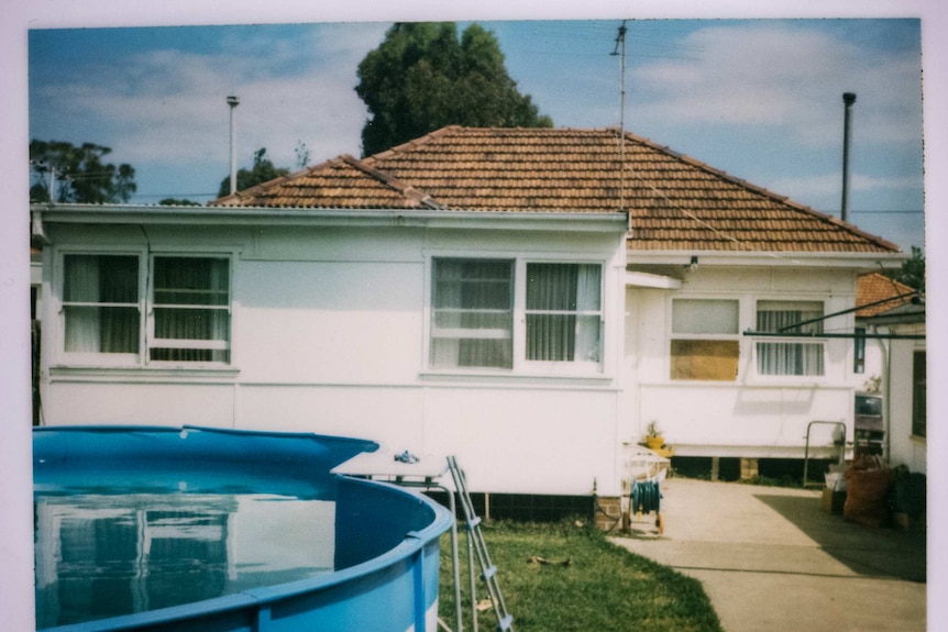 The back of a fibro house with an above ground swimming pool