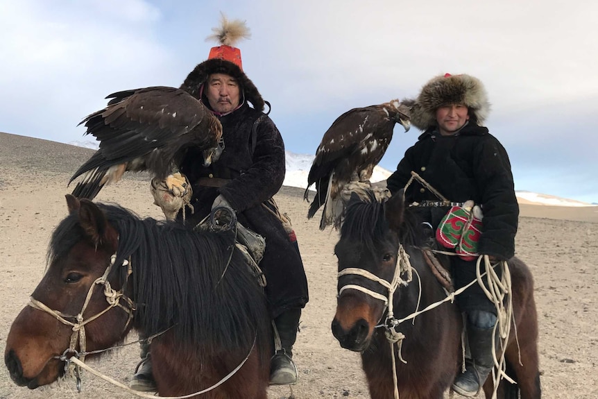 Mongolian eagle hunters riding horses. April 2017.