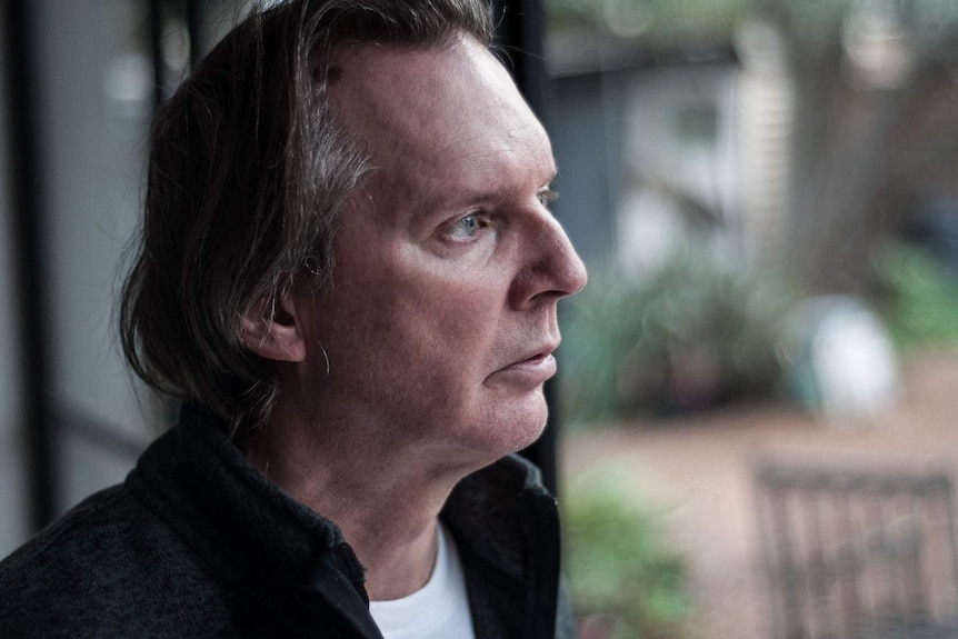 Brett Lockwood gazes thoughtfully at the garden through a window at his home in Melbourne.