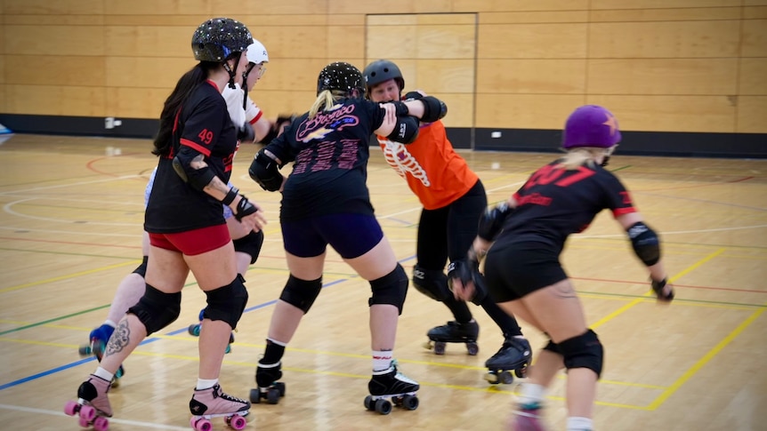 Players grapple with each other in roller derby training at Lightsview