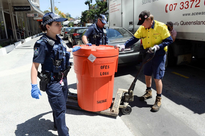 Police remove a bin labelled "toxic" from the apartment.