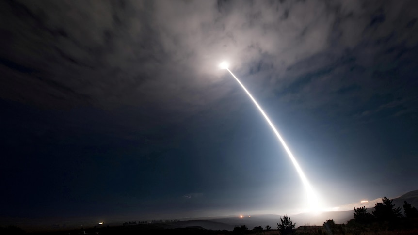 A trail of bright white light in the dark sky follows a missile that has been launched. 