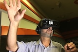 A man wearing a headset stretches out his hand.