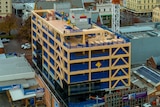 A timber frame surrounds a multi-storey building under construction 