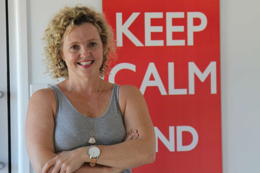 A woman smiles at the camera. She has her arms folded