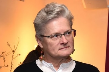 A woman with short grey hair and glasses.