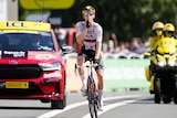 Cyclist gestures to be quiet as he crosses the finish line to win a race