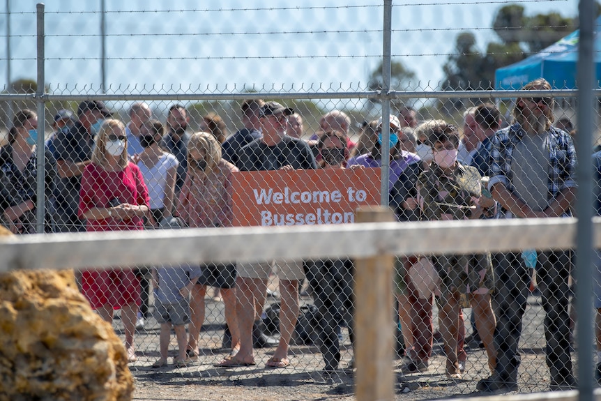 People stand behind a wire fence
