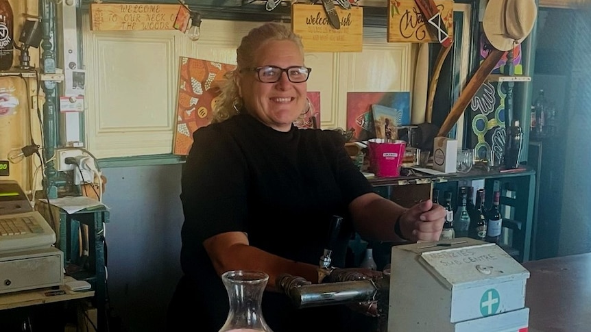 A woman stands behind a bar. 