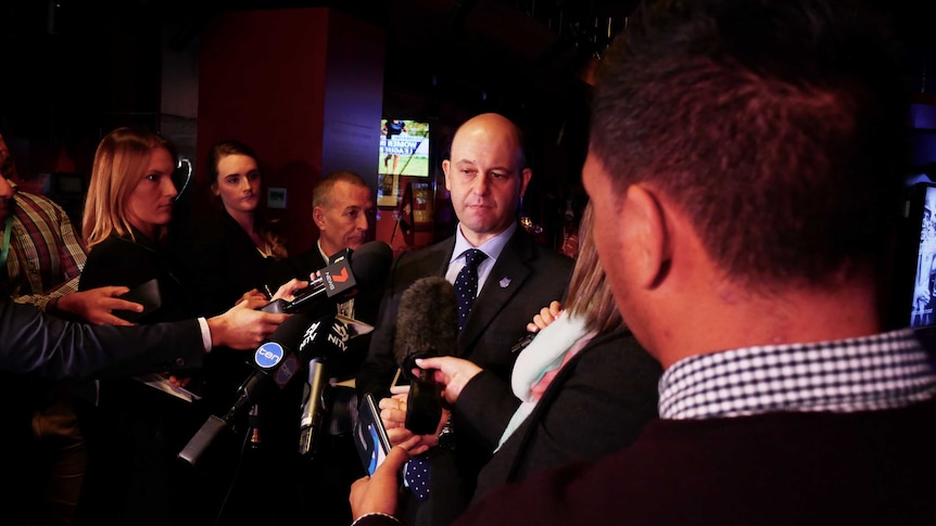 NRL boss stands in front of reporters at a press conference