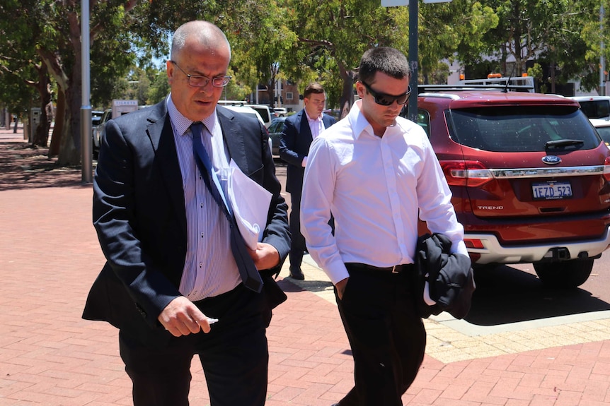 Lawyer John Hammond and client Ricky Swan walk along a footpath outside court with their heads down.