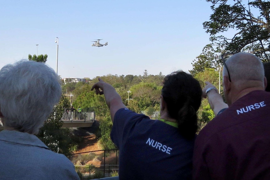 Onlookers at Herston watch as a twin-rotor Osprey precedes the US president's arrival by helicopter.