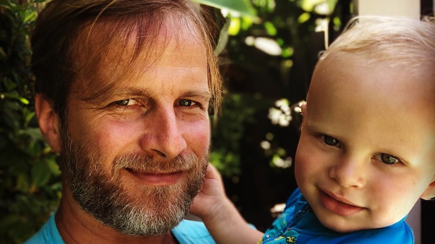 A blonde man cradles a blonde toddler 