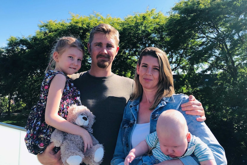 Jennifer Roe holds her infant son as she stands next to her husband, who holds their daughter.