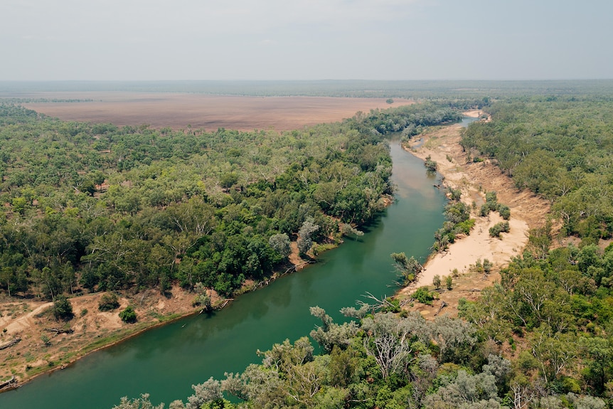 A river winding through bushland with cleared land in the distance.