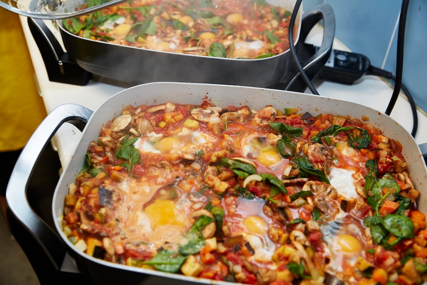 Eggs are poached in a vegetable and tomato sauce in a frypan.
