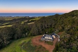 panoramic image of mansion on mountain with sea scape in background