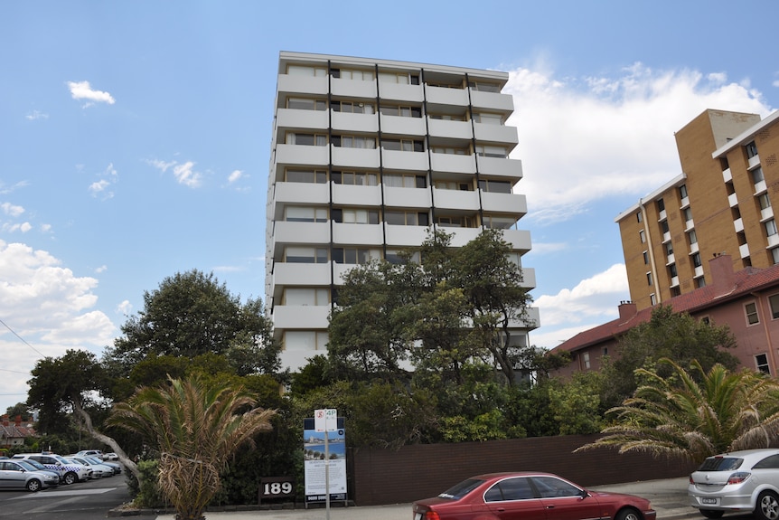 The exterior of an apartment building, with trees in front.