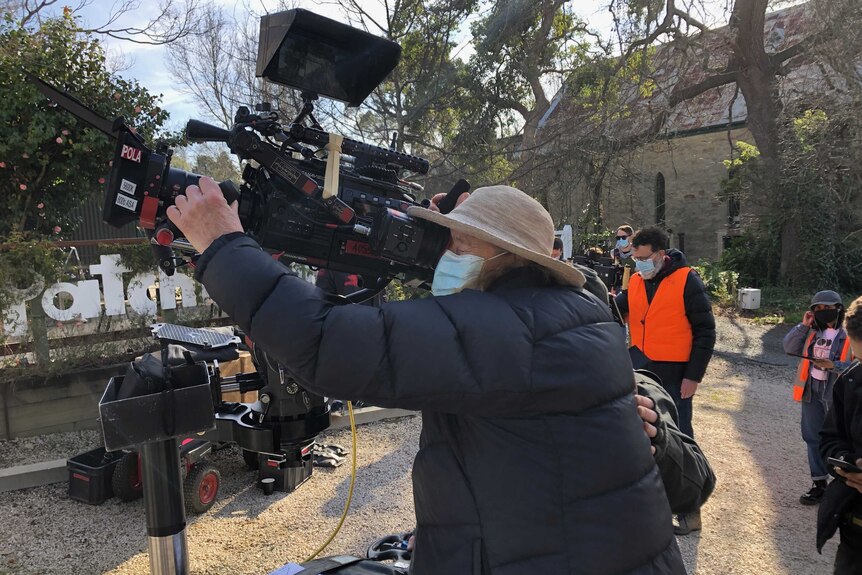 A person looking through a camera while shooting a TV series.