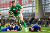 Garry Ringrose screams as he runs with the ball with three France players on the ground behind him