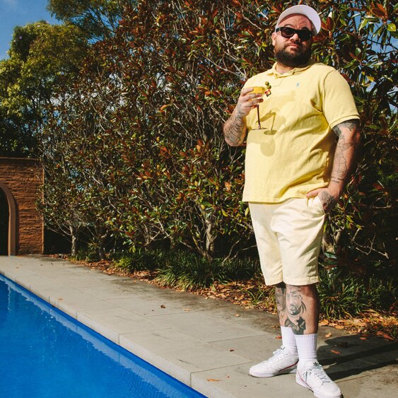 A 2019 press shot of Briggs rocking a tee and white sneakers poolside with a cocktail