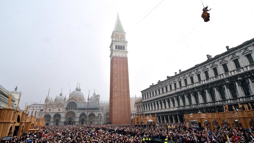 Thousands of people fill Mark's Square in Venice to watch a performance, including a woman flying over them via wire