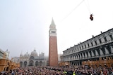 Thousands of people fill Mark's Square in Venice to watch a performance, including a woman flying over them via wire