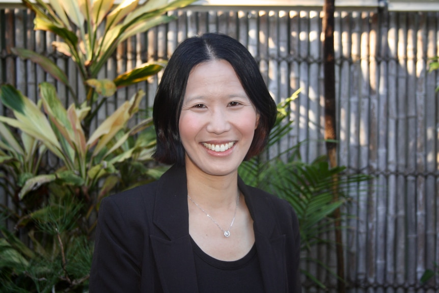 Alice Leung wearing a black jacket and top, smiling in a portrait taken outdoors.