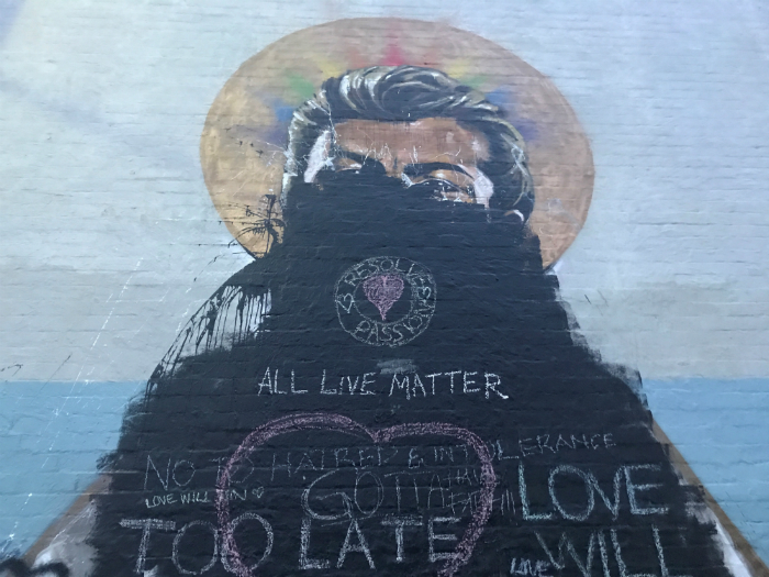 A mural of a man with black paint splashed on it.