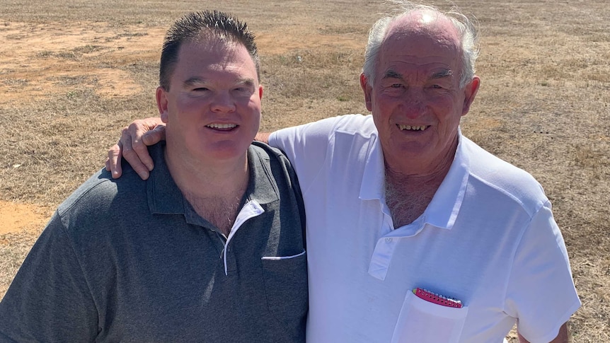 A father and son smile at the camera.