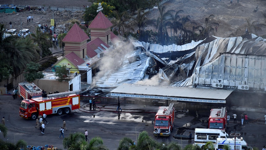 A charred building surrounded by emergency services vehicles after a fire.