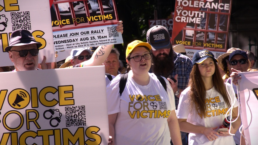 A crowd of people wear shirts that read 'voice for victims' while marching through Brisbane.