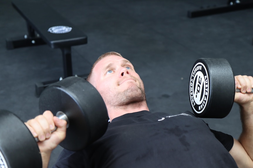 James Smith benchpressing 30 kilogram dumbbells