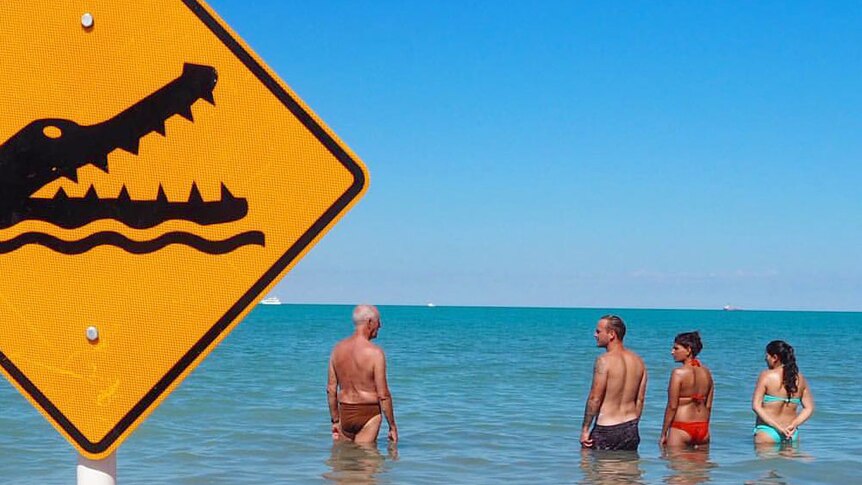 People swimming at Cable Beach in Broome despite a sign warning of crocodiles.