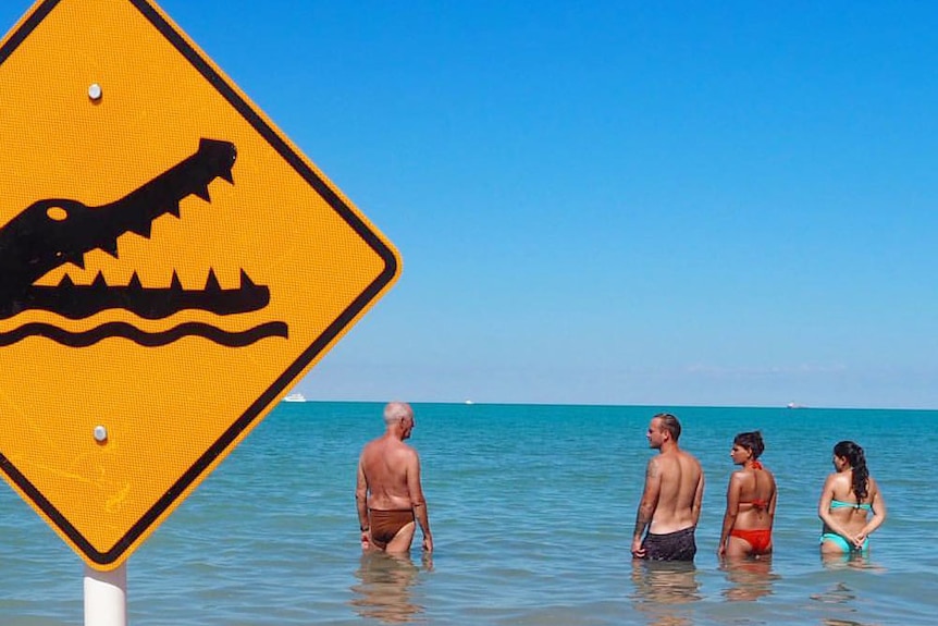 People swimming at Cable Beach in Broome despite a sign warning of crocodiles.